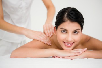 Obraz na płótnie Canvas Pretty brunette enjoying a massage smiling at camera