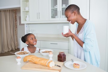 Smiling mother and daughter eating together 