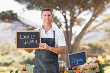 Smiling farmer holding a locally grown sign