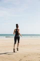 Fototapeta na wymiar Fit woman jogging on the sand