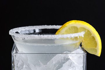 Lemon drop martini on ice with lemon garnish on black background