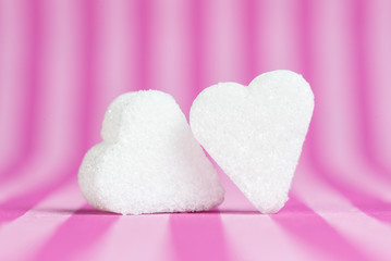 Obraz premium Two white sugar hearts isolated on pink striped background.