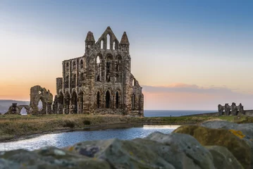 Wall murals Rudnes Stone ruins of Whitby Abbey on the cliffs of Whitby, North Yorkshire, England at sunset.
