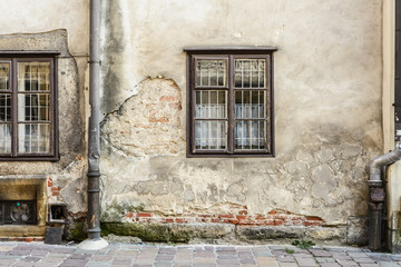 Wall on European city street with windows and crumbling plaster.