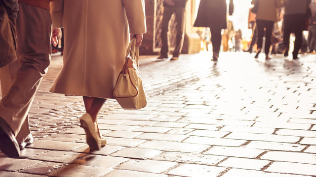 Classy Older European Woman Walking On Stone Tiled Path Holding A Handbag.