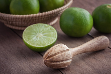 Wooden squeezer and lime on table