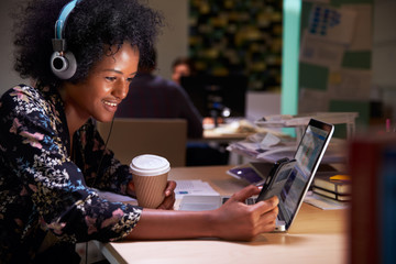 Female Office Worker With Coffee At Desk Working Late