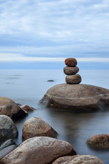 Lake Ladoga in calm cloudy weather. Calm sea and stones built in a row