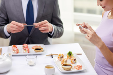 close up of couple with smartphones at restaurant