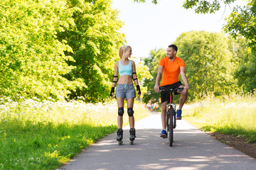 Obraz premium happy couple with rollerblades and bicycle riding