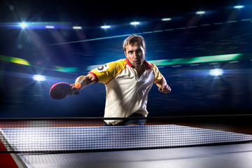 young sports man tennis player playing on black background with