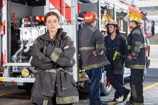 Confident Firewoman With Colleagues Standing By Truck