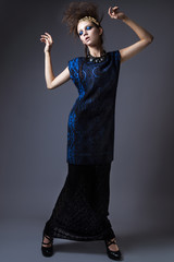 Stylish girl in a fashionable autumn clothes and bright make-up with the wind in her hair. Picture taken in the studio on a gray background.