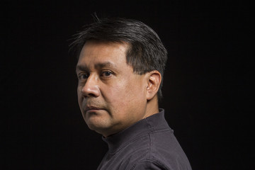 Studio portrait of a serious Hispanic male, over the shoulder