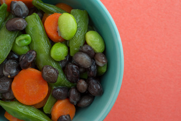Vegetables in a small bowl atop an orange background