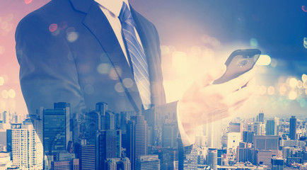 Double exposure of young businessman holding a smartphone