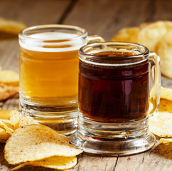 Dark and light beer and chips on the old wooden background, sele