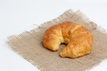 one croissant on spuare frayed burlap