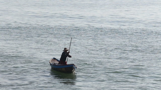 vietnamese fisherman drifts in boat using stick