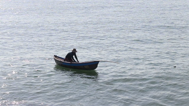 vietnamese fisherman rows in boat using paddle
