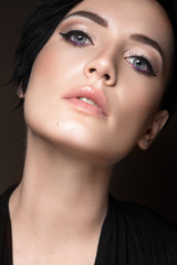 Obraz premium Preview Stock Photo: Beautiful brunette girl with evening make-up and perfect skin. Beauty face. Picture taken in the studio on a black background.