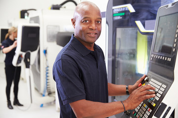 Portrait Of Male Engineer Operating CNC Machinery In Factory