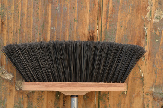 Besen vor alter Holzwand