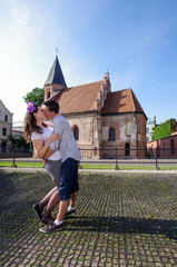 Fototapeta premium Young couple kissing near church at their wedding anniversary