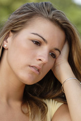 A young woman with hand on head.