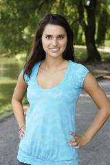 Fototapeta premium Beautiful young woman smiles at viewer. Hands on hips.