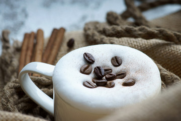 Coffee cup, rope, coffee beans and cinnamon on burlap sack