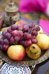 Wedding table arrangement in desert sand of Morocco stile. Fresh grapes near the salver with apples and pears 