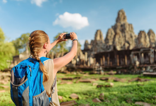 Female tourist taking picture of Bayon temple. Angkor, Cambodia