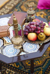 Wedding table arrangement in desert sand of Morocco stile. Fresh grapes near the salver with apples and pears