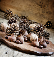 Fir cones, nuts, chocolate truffles and candy on the old wooden