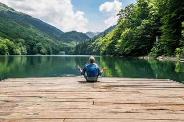 The man meditating in lotus position on Biogradsko lake in the n