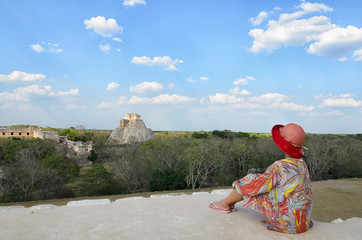 Anonymous Woman in colorful dress and red hat sitting on the edge 