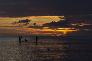 People paddle boarding during sunset