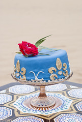 Blue wedding cake on a table and red roses on top in the desert landscape 