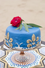 Blue wedding cake on a table and red roses on top in the desert landscape 