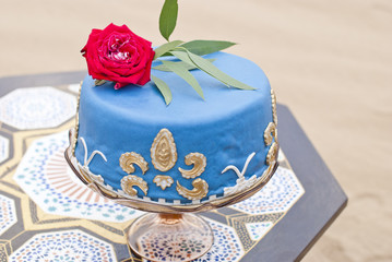 Blue wedding cake on a table and red roses on top in the desert landscape