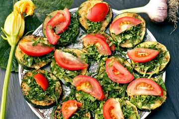 Fried zucchini with green and tomatoes on plate