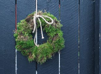 The wreath of moss hanging on the wooden wall