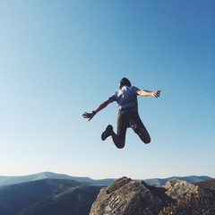 extreme man jump with rock in mountains
