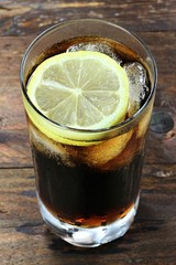 Cola mit Eiswürfeln und Zitronenscheibe auf Holztisch