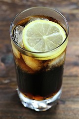 Cola mit Eiswürfeln und Zitronenscheibe auf Holztisch
