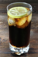 Cola mit Eiswürfeln und Zitronenscheibe auf Holztisch