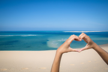 Hands making a heart sign at the beach of the Bazaruto Islands near Vilanculos in Mozambique with...