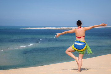 Fototapeta na wymiar Girl in a standing yoga pose in the beach of the Bazaruto Islands near Vilanculos in Mozambique with the Indian ocean in the background