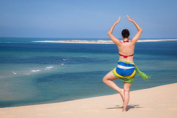 Fototapeta na wymiar Girl in a standing yoga pose in the beach of the Bazaruto Islands near Vilanculos in Mozambique with the Indian ocean in the background